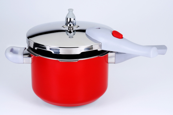 A red pressure cooker on a table.