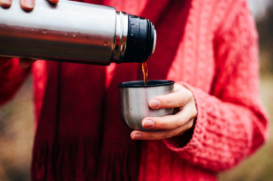 A women pulling hot tea from a stainless steel travel mug.