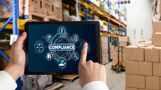 A man handling a pad in a warehouse with text COMPLIANCE on it