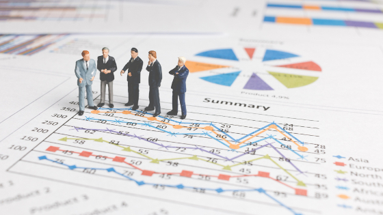 Human figures in suits standing on a line chart discussing