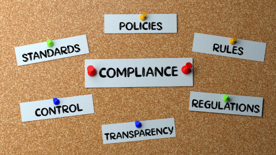 A cork board with papers on it that says compliance and policies