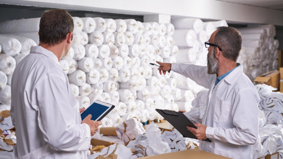 Two men in uniform checking raw fabric rows