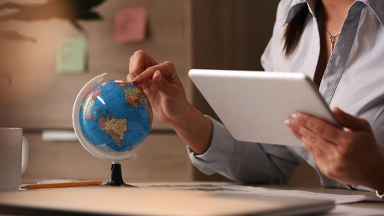 Businesswoman using digital tablet while examining globe and planning sourcing location