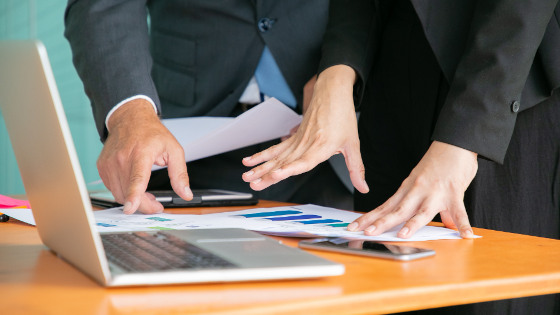 Unrecognizable businesspeople studying statistics and holding papers with hands