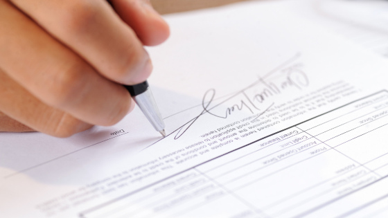 A person signing a document with signature