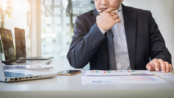 A businessman is working at a table and looking at some data to make business decision